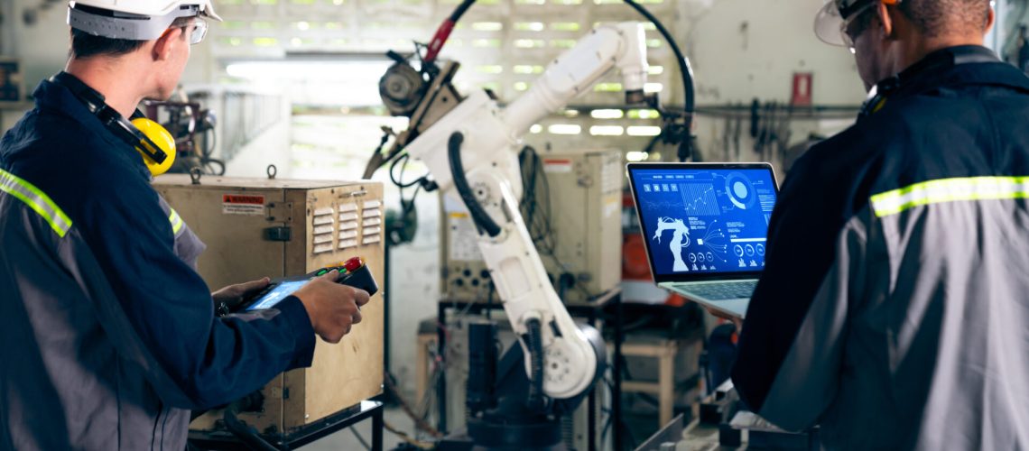 Factory workers working with adept robotic arm in a workshop